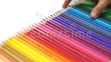 女人的手拿起彩色铅笔安排在白色的桌子上